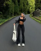 Conjunto deportivo compuesto por un top de manga larga con escote cuadrado y un pantalón tipo legging acampanado de tiro alto, ambos en color negro.