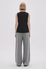 Chaleco negro sin mangas, con cuello redondo y cierre frontal de botones. Presenta un diseño entallado con bolsillos laterales simulados.