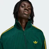 Campera deportiva Adidas Firebird de color verde oscuro con textura de rayas de tiza y detalles en amarillo, incluyendo las clásicas tres tiras en las mangas y el logo del trifolio bordado en el pecho. Cuenta con cuello alto, cierre frontal completo y bolsillos laterales.