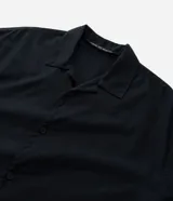 Camisa de manga corta color negro, con diseño boxy, cuello clásico y abotonado frontal.