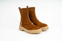 Bota tipo borcego de caña media, confeccionada en una combinación de cuero gamuzado negro y detalles en cuero color suela en la parte trasera y lengüeta. Presenta suela track de goma negra y costuras a la vista.