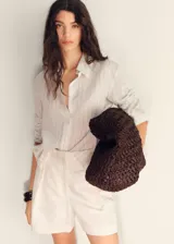 Short de tiro alto con diseño recto estilo sastre, confeccionado en tejido mezcla de lino. Cuenta con cierre delantero de cremallera, doble gancho y botón interior, además de trabillas para cinturón y dos bolsillos laterales.