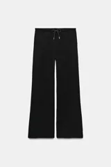 Pantalón flare negro confeccionado en tejido de punto elástico. Presenta tiro medio, cintura elástica ajustable con cordón y bolsillos delanteros.