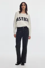 Jean flare de tiro medio, color negro con efecto gastado y estampado de lunares metalizados distribuidos por toda la prenda.