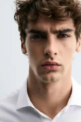 Camisa de corte regular fit confeccionada en tejido de algodón con textura. Presenta cuello clásico, manga larga con puños abotonados y cierre frontal con botones.