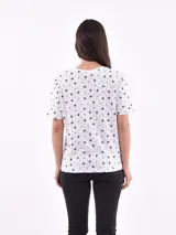 Remera de manga corta color beige con estampado de bananas en tonos amarillo, naranja y rosado.