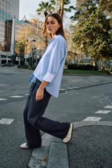 Camisa básica de algodón con cuello solapa, escote en pico y cierre frontal con botones. Presenta mangas largas con puños abotonados y bajo redondeado.