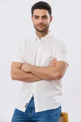 Camisa lisa de manga corta y corte slim fit, color blanco, con cuello camisero, cierre frontal de botones y bolsillo ojal en el pecho.