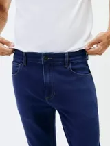 Pantalón de jean corte skinny, color azul medio, con diseño de cinco bolsillos y cierre frontal con botón y cremallera.