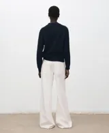 Sweater de punto color azul marino con cuello redondo y mangas largas. Presenta una línea vertical blanca contrastante que recorre el hombro y la parte superior de la manga.