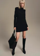 Vestido corto negro de manga larga con cuello drapeado y diseño recto.
