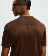 Remera deportiva de manga corta y cuello redondo, confeccionada en tejido de malla de poliéster. Presenta un diseño liso en color marrón con recortes laterales en poliamida.