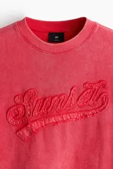 Remera boxy de algodón liviano en color coral, con efecto acid wash, hombros caídos, cuello redondo ribeteado y corte oversized. Cuenta con bordado en relieve con la palabra 'Sunset' en el frente.