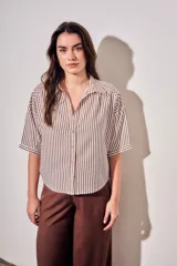 Camisa de corte oversize con estampado de rayas verticales en tonos marrón y beige. Presenta cuello camisero, cierre frontal con botones y mangas cortas con caída relajada.