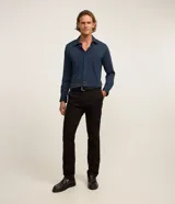Pantalón slim de sarga color negro, con cierre de botón y cremallera, y bolsillos funcionales.
