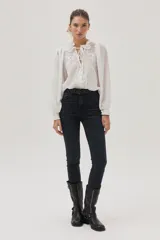 Blusa blanca con lunares en relieve, cuello con volados y lazos, mangas abullonadas 3/4 y bordados con lentejuelas en el frente.