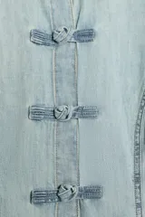 Camisa de denim celeste con cuello solapa, manga larga y cierre frontal con nudos de tela.