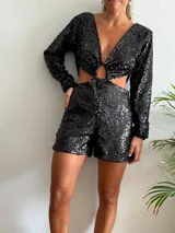 Mono corto negro de lentejuelas con escote en V, mangas largas y abertura en la cintura.