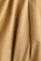 Pollera mini acampanada en sarga de algodón y lyocell, de cintura estándar con cierre, pretina prolongada con botones y elástico revestido en los lados. Cuenta con frunces en la parte superior y bolsillos laterales discretos.