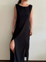 Vestido largo negro de tejido texturizado, sin mangas y con escote bote. Presenta dos tajos laterales altos.
