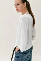 Top fluido de punto liso en color blanco, con escote en V pronunciado y mangas cortas amplias.