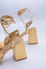 Sandalias color beige con plataforma y tacón cuadrado. Presentan tiras cruzadas en el empeine y tiras largas para atar alrededor del tobillo.