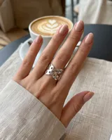 Anillo ancho de acero plateado con diseño calado de perforaciones geométricas.