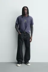 Camiseta de corte relajado con cuello redondo y manga corta. Presenta un acabado con efecto lavado que le otorga una apariencia única y desgastada. Incluye estampados a contraste en la parte frontal.