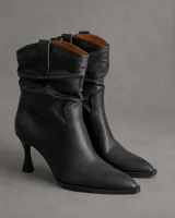 Bota texana de caña media con diseño fruncido en la parte superior, confeccionada en cuero negro. Presenta punta fina, taco aguja de altura media y tiradores laterales.