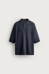 Polo de punto de algodón color gris oscuro con textura acanalada horizontal, cuello solapa y cierre frontal de botones. Cuenta con mangas cortas y acabados en rib.