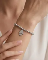 Pulsera de acero quirúrgico compuesta por pequeñas cuentas esféricas y un dije colgante en forma de mano de Fátima (Hamsa).