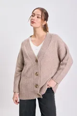 Cardigan de punto en color beige, con escote en V, cierre frontal de botones y mangas largas con puños acanalados.