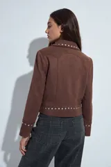 Campera estilo biker de símil gamuza color marrón, con cierre frontal y detalles de tachas metálicas en solapas, mangas y ruedo.