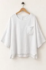 Remera blanca de algodón, de corte holgado y diseño oversize, con mangas anchas de tres cuartos, escote redondo con pequeña abertura trasera tipo ojal y un bolsillo aplicado en el pecho.