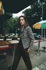 Chaqueta de tweed en tonos gris y negro, con cuello desmontable de pelo sintético marrón, bolsillos delanteros de plastrón y acabados deshilachados.