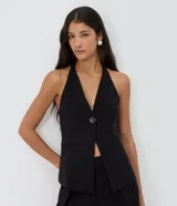 Chaleco sastrero halter negro con escote en V profundo, un botón central y bolsillos ribeteados simulados.