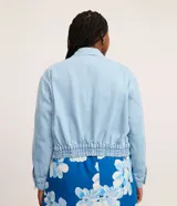 Campera de jean celeste de algodón con cuello inglés, abotonada, de manga larga ajustada con elástico en la cintura.