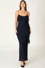 Vestido largo de fiesta color azul marino, con breteles finos, escote recto y detalle de volados laterales que recorren el frente de la prenda. Confeccionado en tela fluida con caída suave.