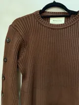 Sweater color camel de tejido de punto acanalado, con cuello redondo y botones decorativos en las mangas. Hecho en Uruguay.