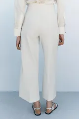 Pantalón tipo culotte de tiro alto, pierna ancha y pinzas frontales. Color beige/topo liso.