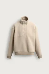Sudadera de hombre con corte relajado, confeccionada en tejido texturizado tipo borreguillo color beige. Presenta cuello subido, cierre frontal parcial con botones a presión y puños y dobladillo acanalados.