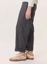 Pantalon de corte recto y tiro medio, confeccionado en tejido de lana con sutiles rayas verticales. Presenta bolsillos traseros aplicados, costuras reforzadas en las rodillas y ruedo con dobladillo.