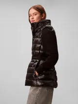 Chaleco puffer liviano marca Calvin Klein color negro, con diseño acolchado, capucha, cierre frontal y cinturón elástico con hebilla a presión y logo de la marca.