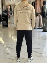 Canguro beige liviano sin felpa, con capucha y estampado en la espalda con el texto "Original Studio Copenhagen Workshop Crafted Aesthetics".
