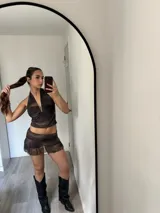 Conjunto de dos piezas compuesto por un top halter con cierre frontal y una minifalda con volado en el ruedo, confeccionado en tela semitransparente con estampado abstracto en tonos marrones.