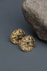 Aros tipo botón dorados con textura irregular que simula la superficie de un molusco.