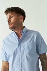 Camisa de manga corta con estampado de cuadros vichy en azul y blanco. Presenta cuello con botones, cierre frontal con botones y logo bordado en el pecho.