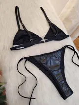 Conjunto de bikini negro con acabado efecto cuero, compuesto por un corpiño triangular con cierre frontal metálico y bombacha tipo vedetina con tiras laterales ajustables.