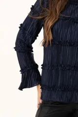 Blusa de manga larga en color azul marino, confeccionada en tejido plisado con detalles de volados horizontales a lo largo de toda la prenda.