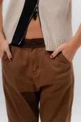 Pantalón de gabardina azul marino, de corte barrel y tiro bajo, con detalles en pana marrón en la pretina y en el ruedo interior vuelto.